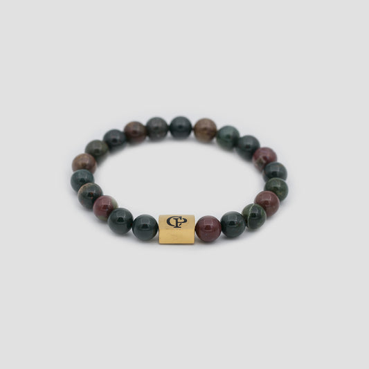 Red and Green Bloodstone Elastic Golden Bracelet on a gray surface