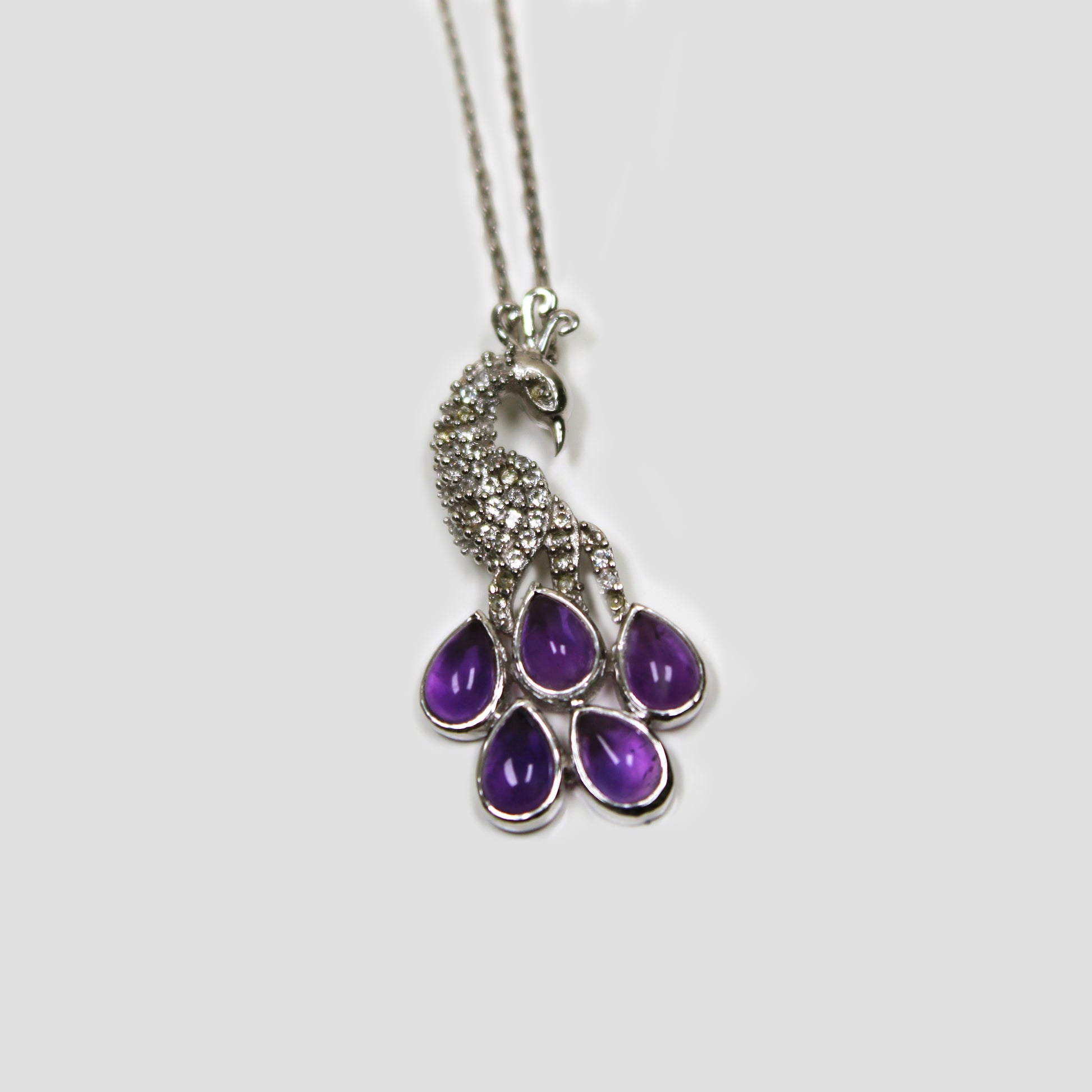 Purple Amethyst Peacock with White Topaz Necklace on a gray surface