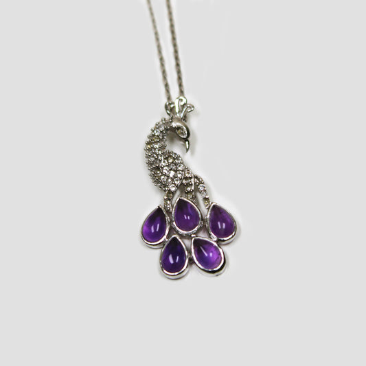 Purple Amethyst Peacock with White Topaz Necklace on a gray surface