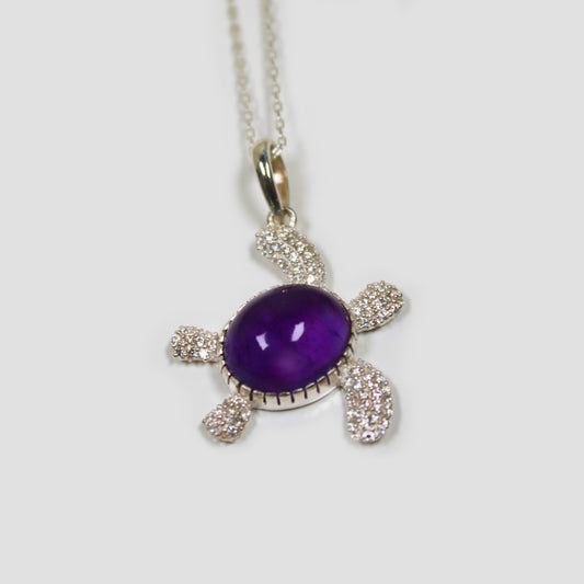 Purple Amethyst Turtle with White Topaz Necklace on a gray surface