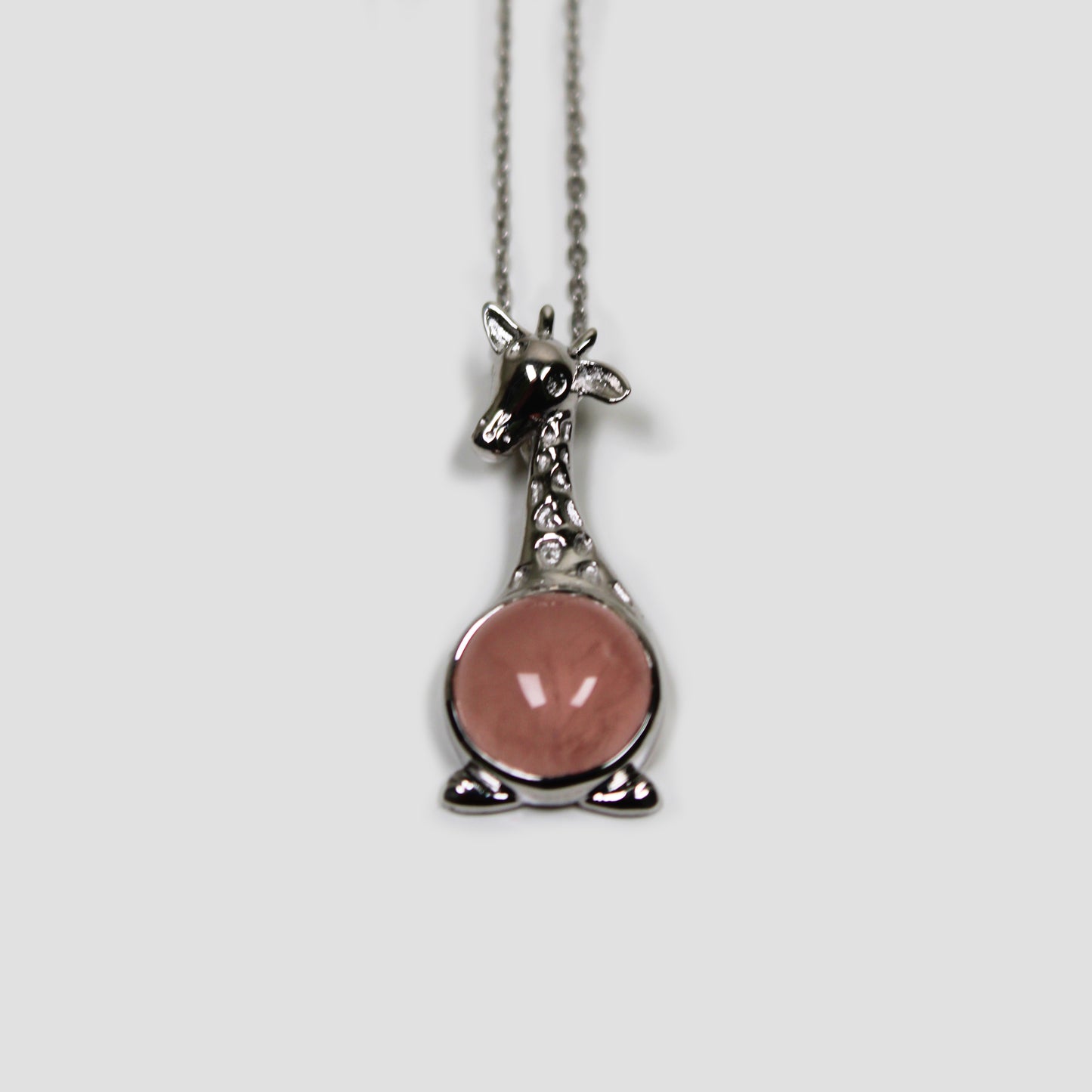 Rose Quartz Giraffe with White Topaz Necklace on a gray surface