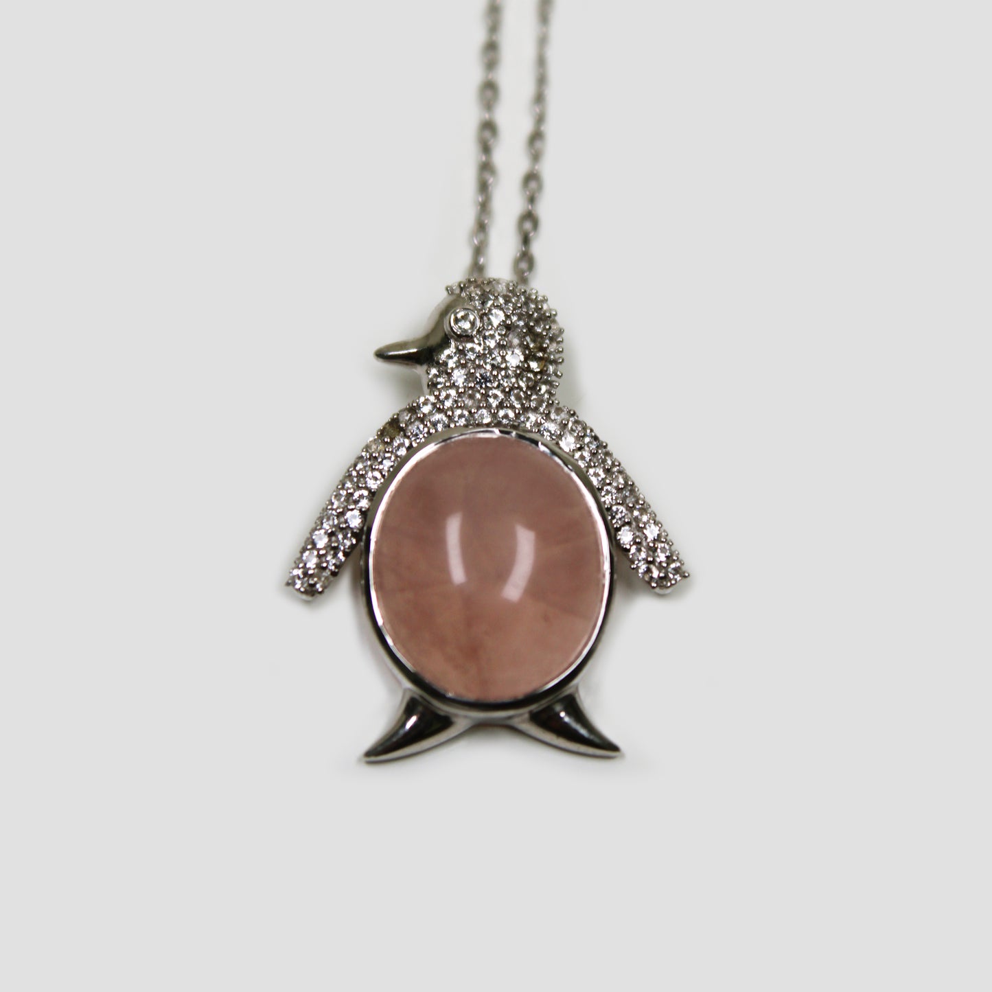 Rose Quartz Penguin with White Topaz Necklace on a gray surface