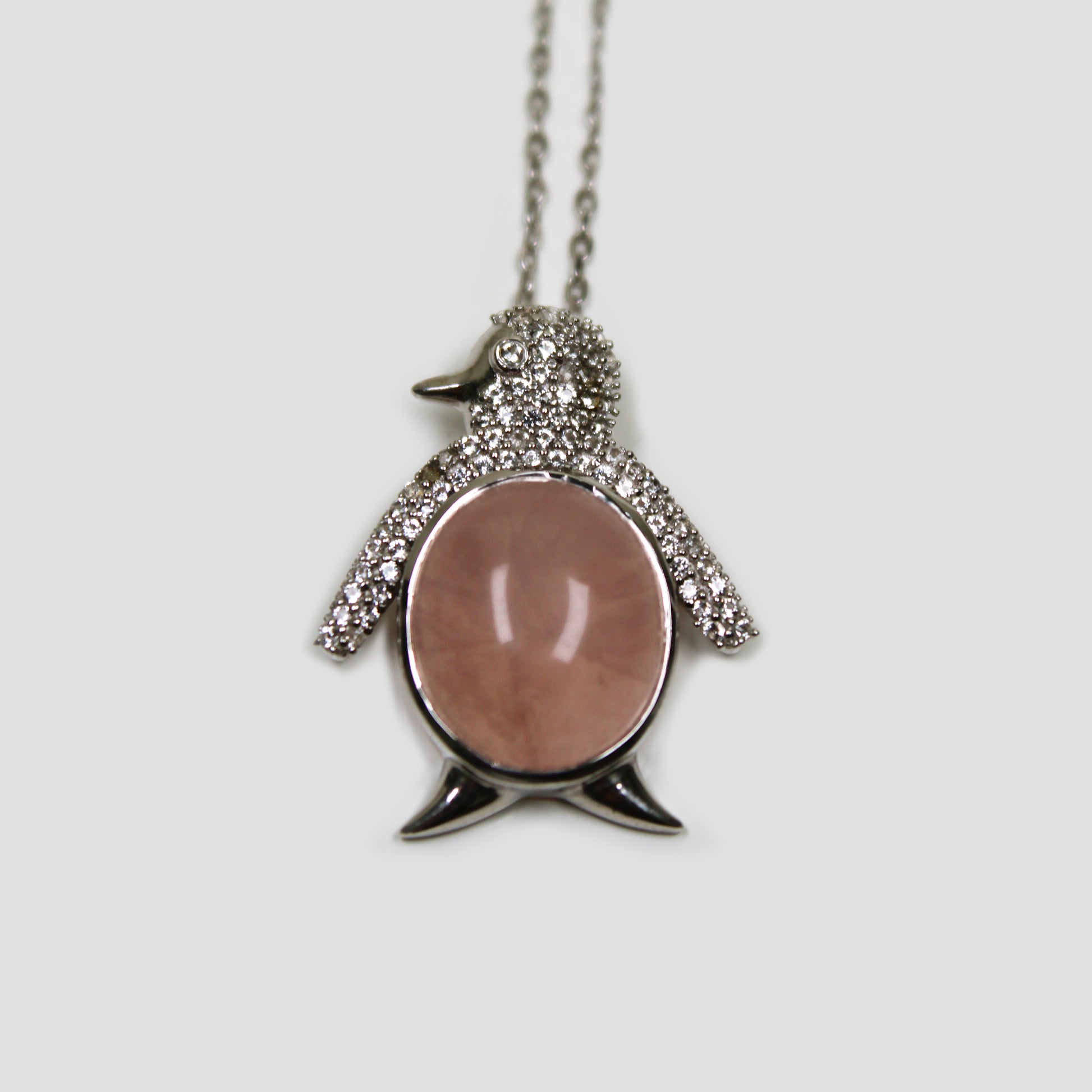 Rose Quartz Penguin with White Topaz Necklace on a gray surface