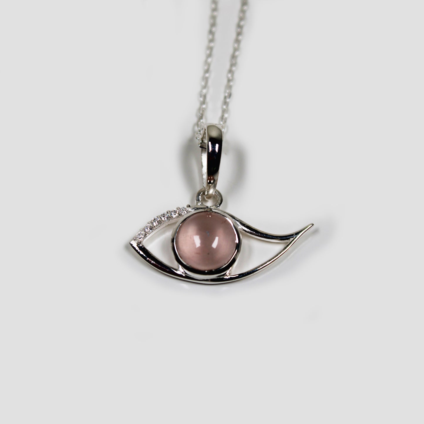 Rose Quartz Ra Eye with White Topaz on a gray surface