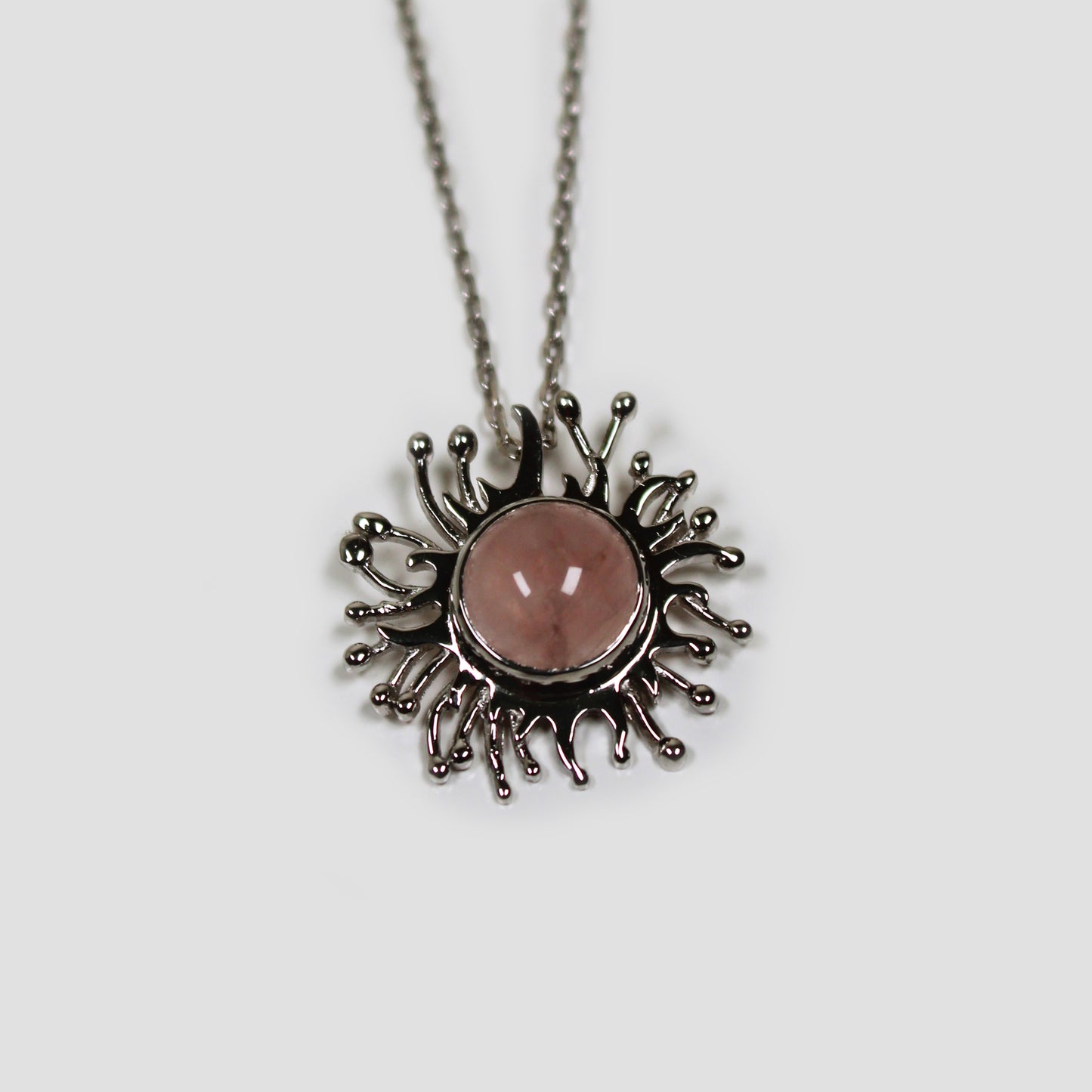 Rose Quartz Solaire Necklace on a gray surface