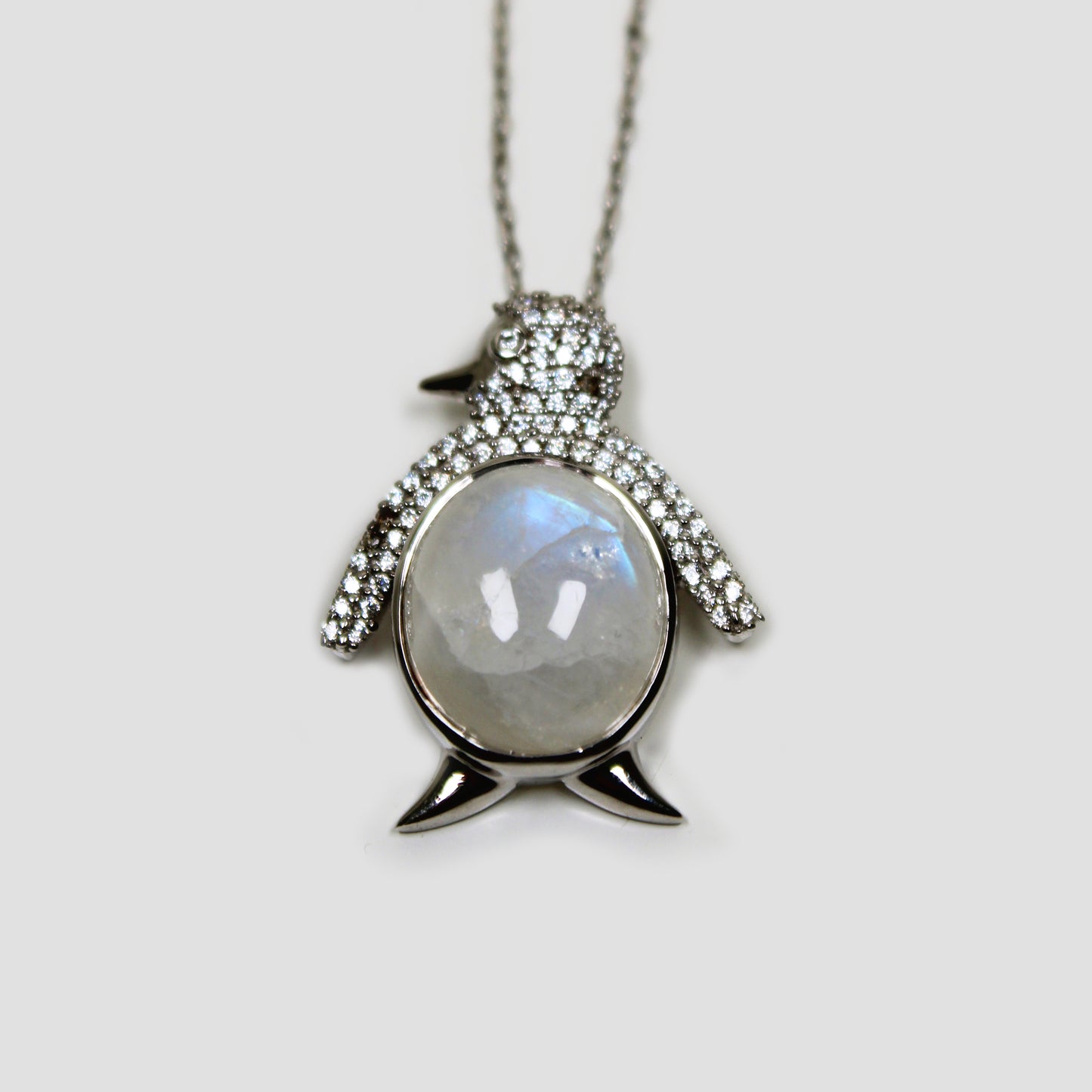 Moonstone Penguin with White Topaz Necklace on a gray surface