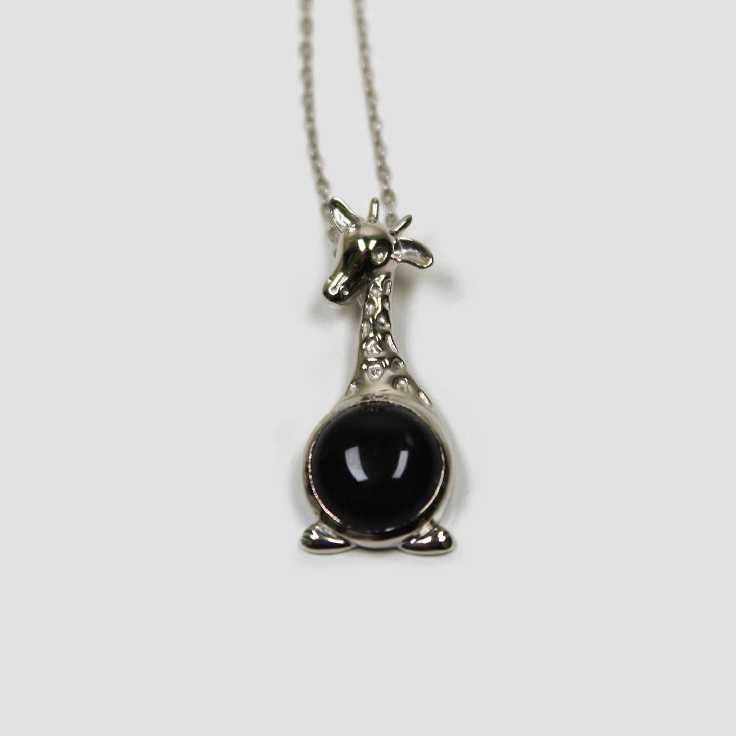 Black Onyx Giraffe with White Topaz Necklace on a gray surface