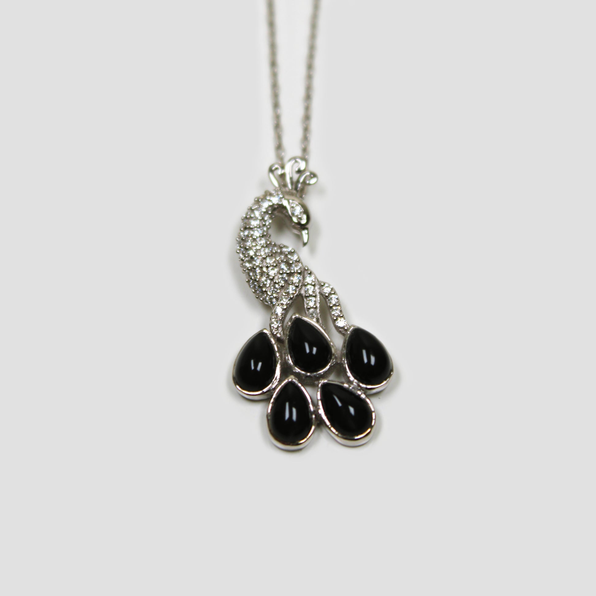 Black Onyx Peacock with White Topaz on a gray surface