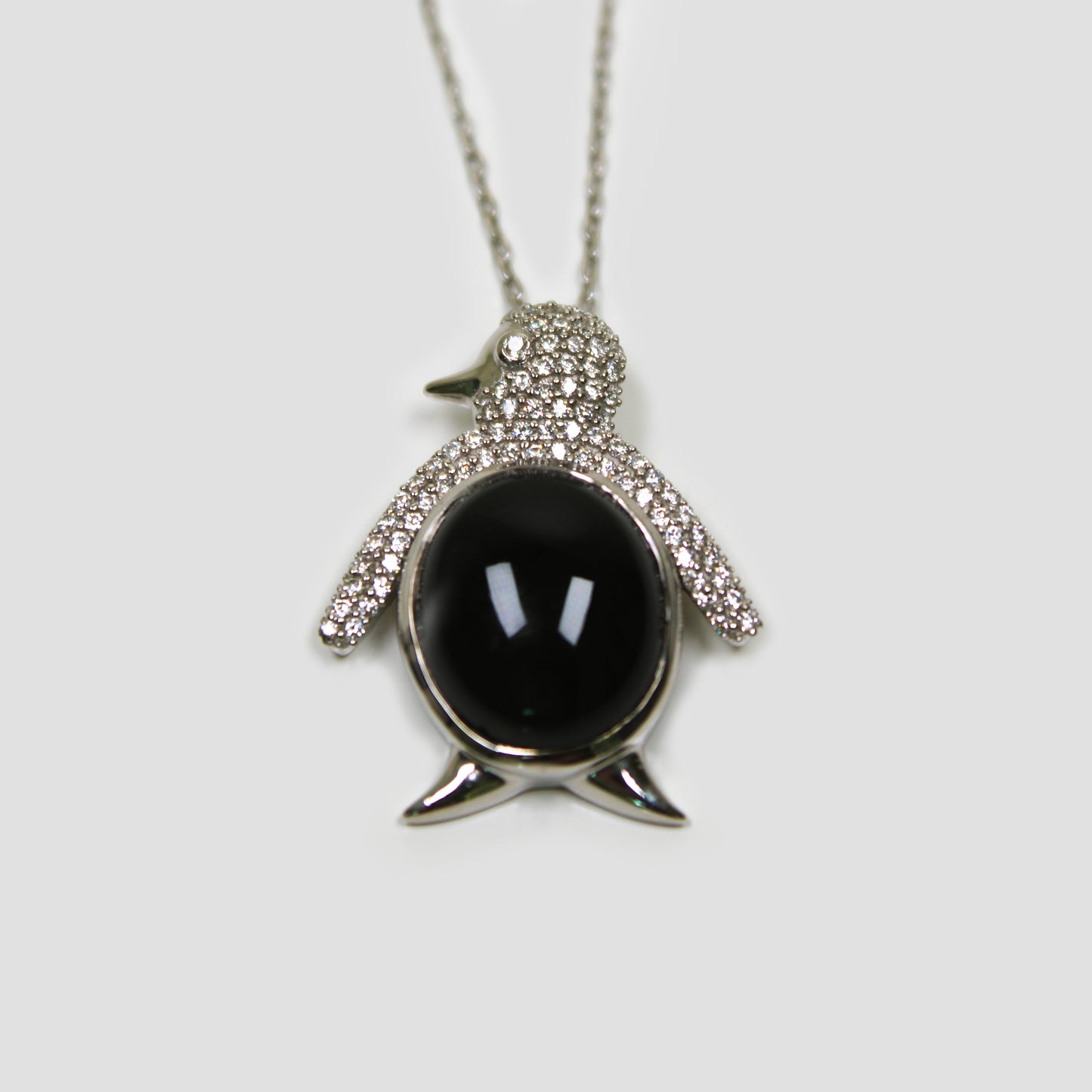 Black Onyx Penguin with White Topaz Necklace on a gray surface