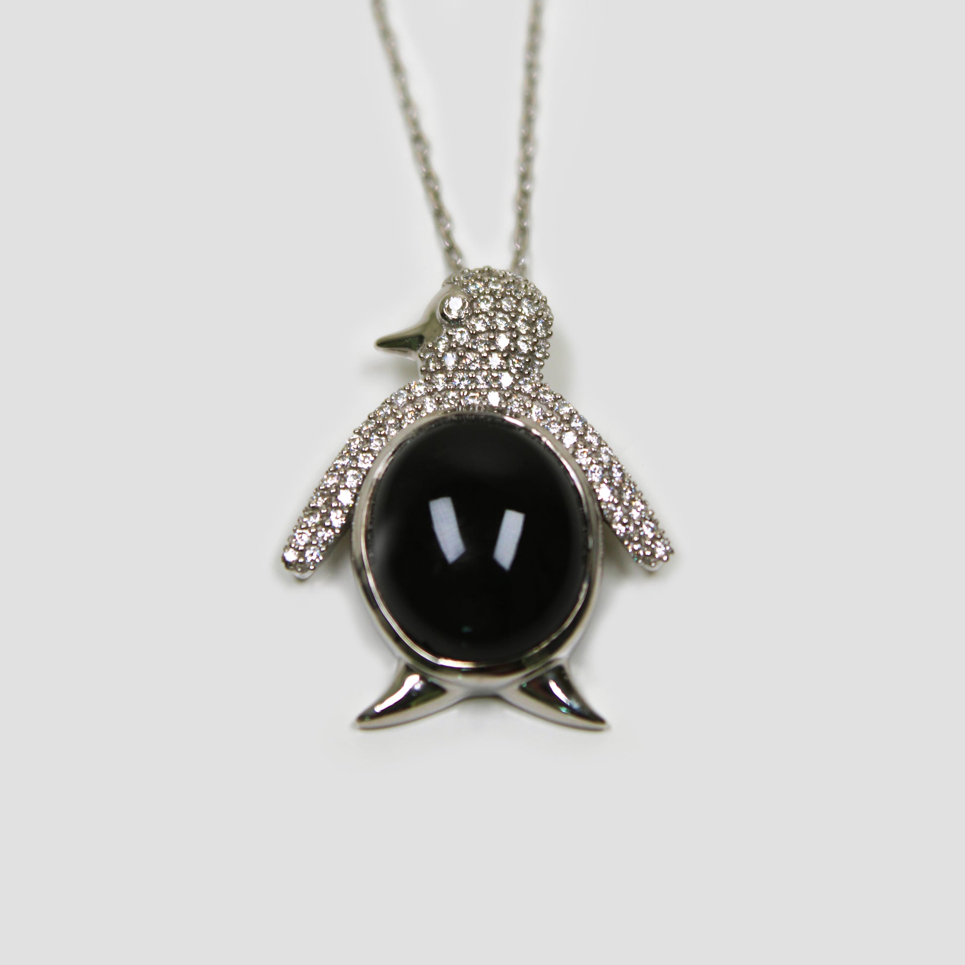 Black Onyx Penguin with White Topaz Necklace on a gray surface