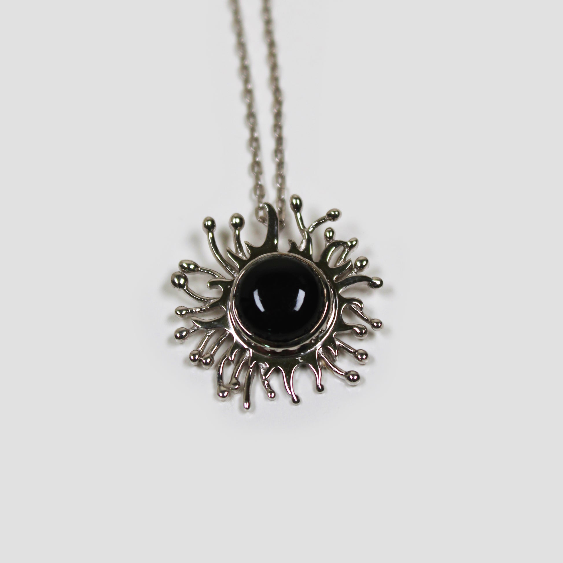 Black Onyx Solaire Necklace on a gray surface