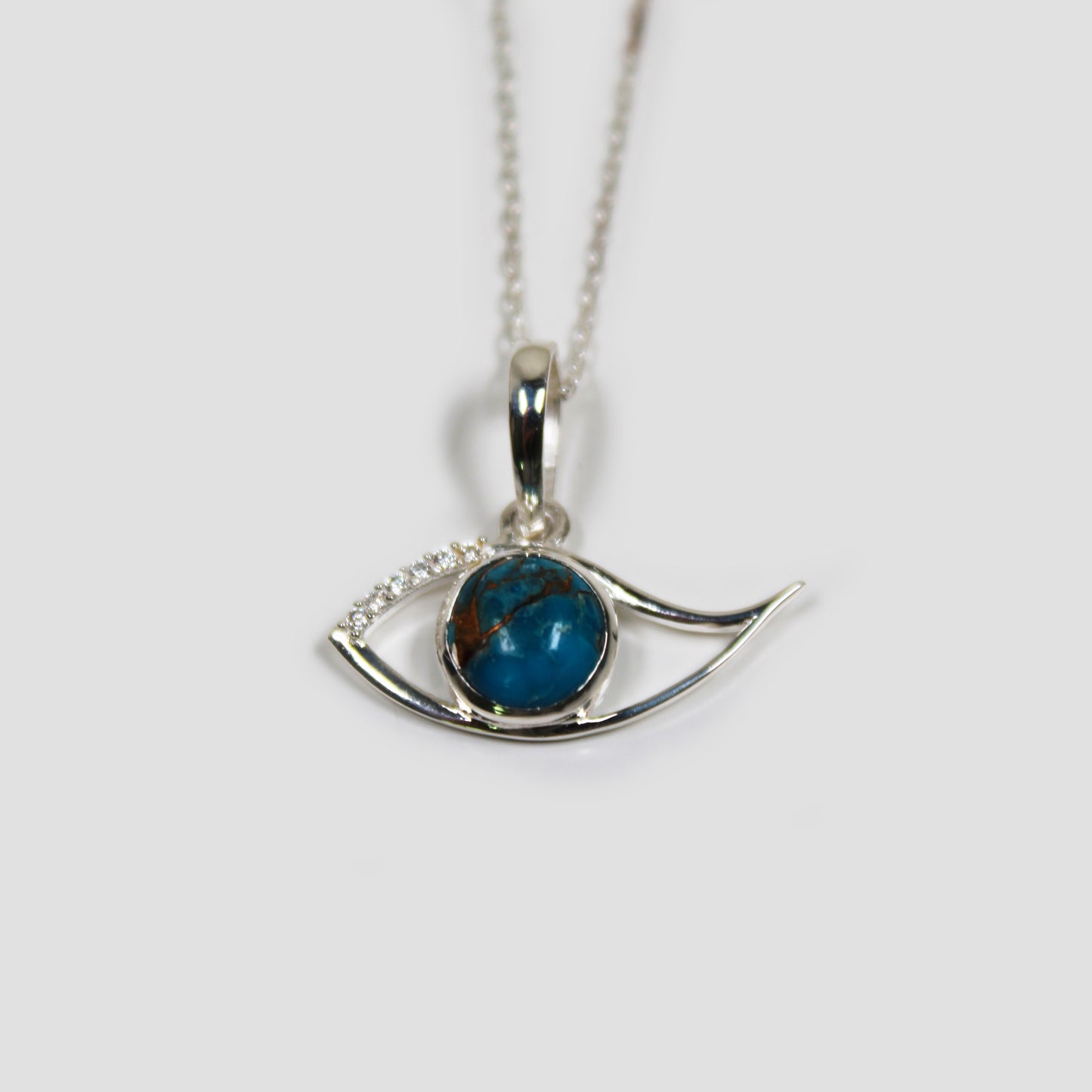 Blue Copper Turquoise Ra Eye with White Topaz on a gray surface