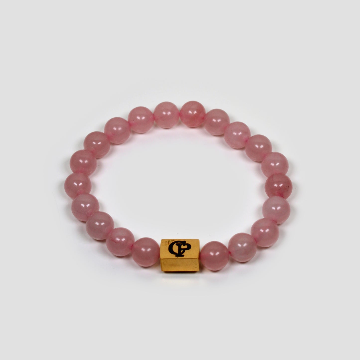 Rose Quartz Elastic Golden Bracelet on a gray surface