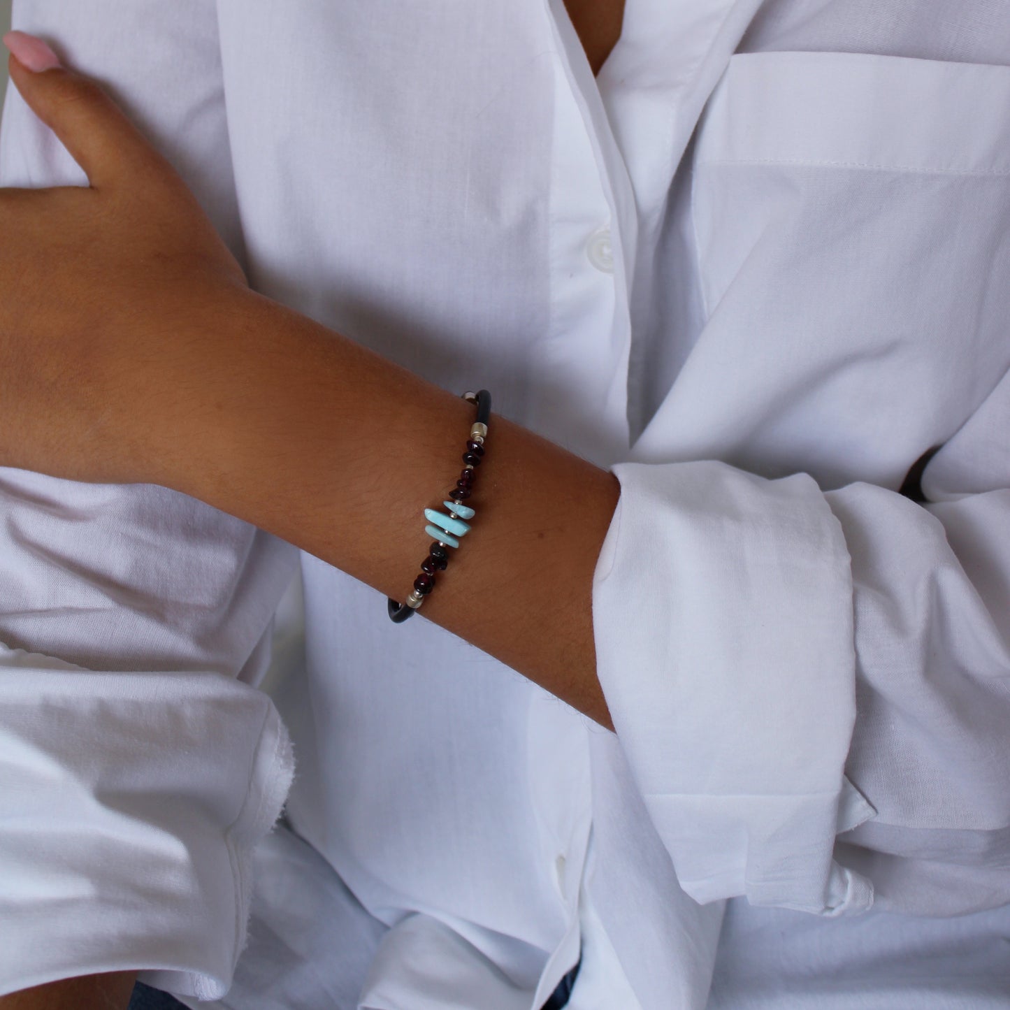 A woman wearing Larimar Garnet Leather Cord Bracelet on her wrist