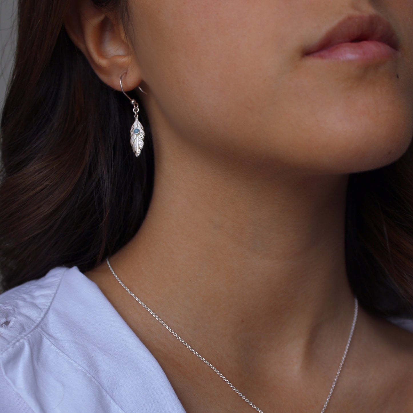 A woman wearing Larimar Feather Silver Earrings