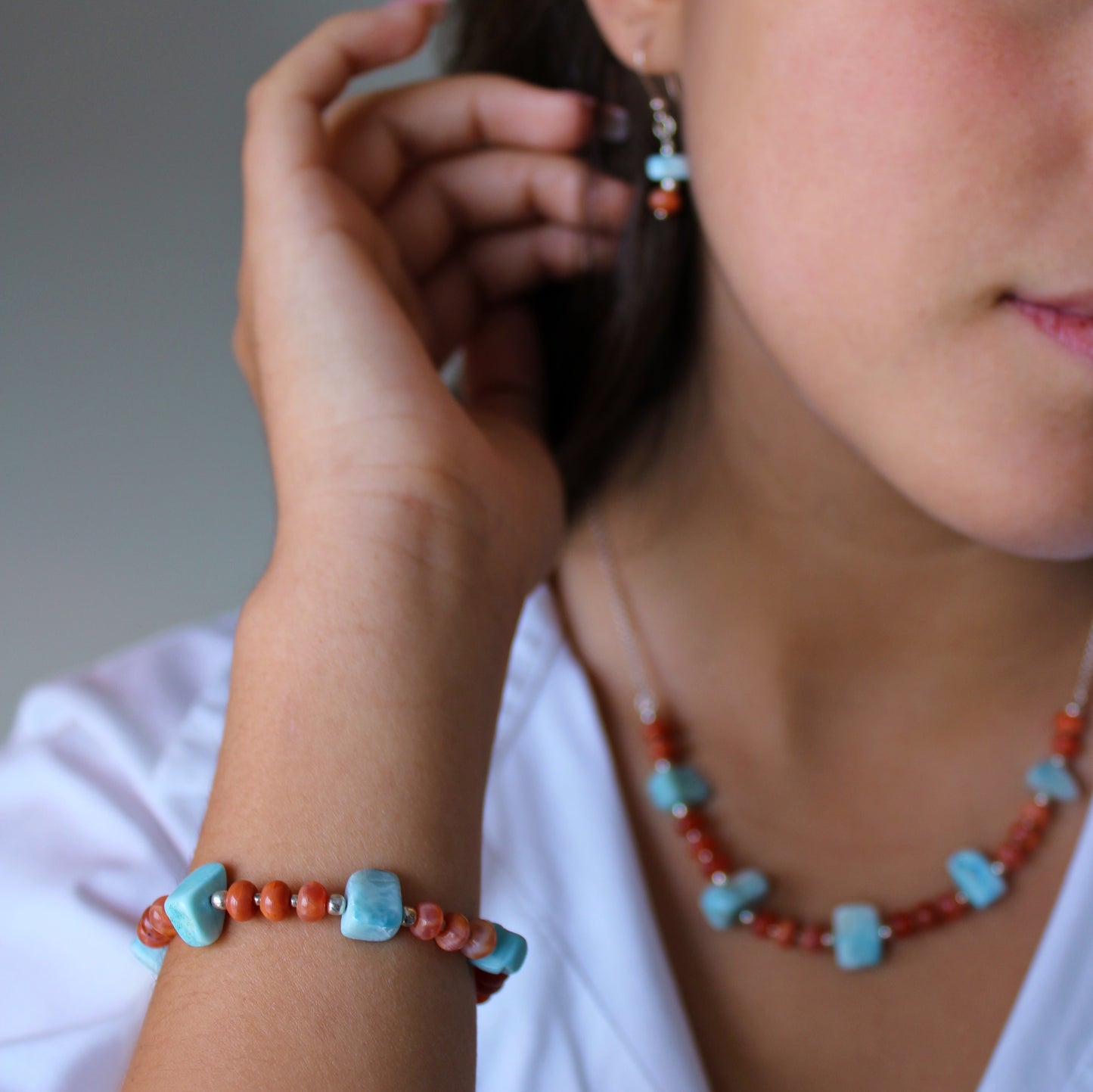 A woman wearing Larimar & Carnelian Bracelet, Necklace and Earrings